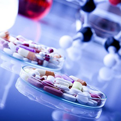 Picture of pills in a petri dish and a molecule model in the background 